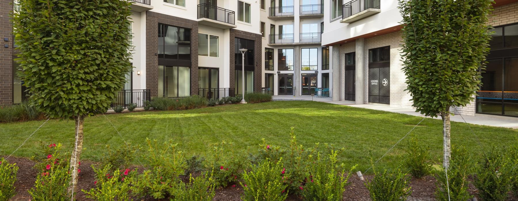 a courtyard with trees and plants in front of a building